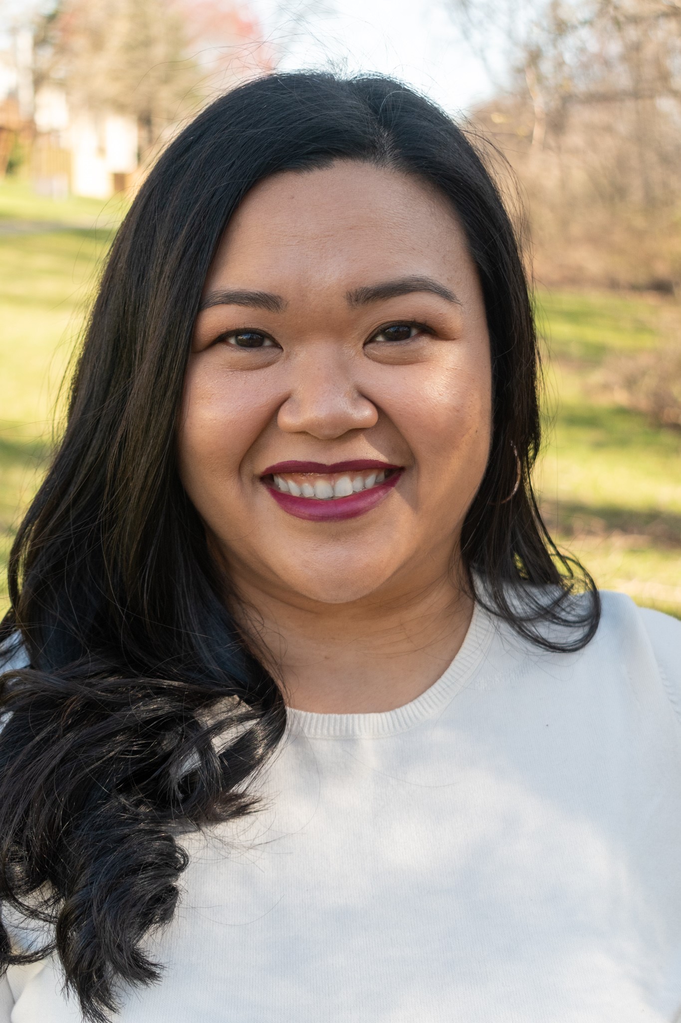 Head shot of Elaine de Leon Ahn smiling in a field