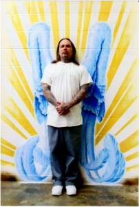 A photo of Dewy standing in front of mural. 